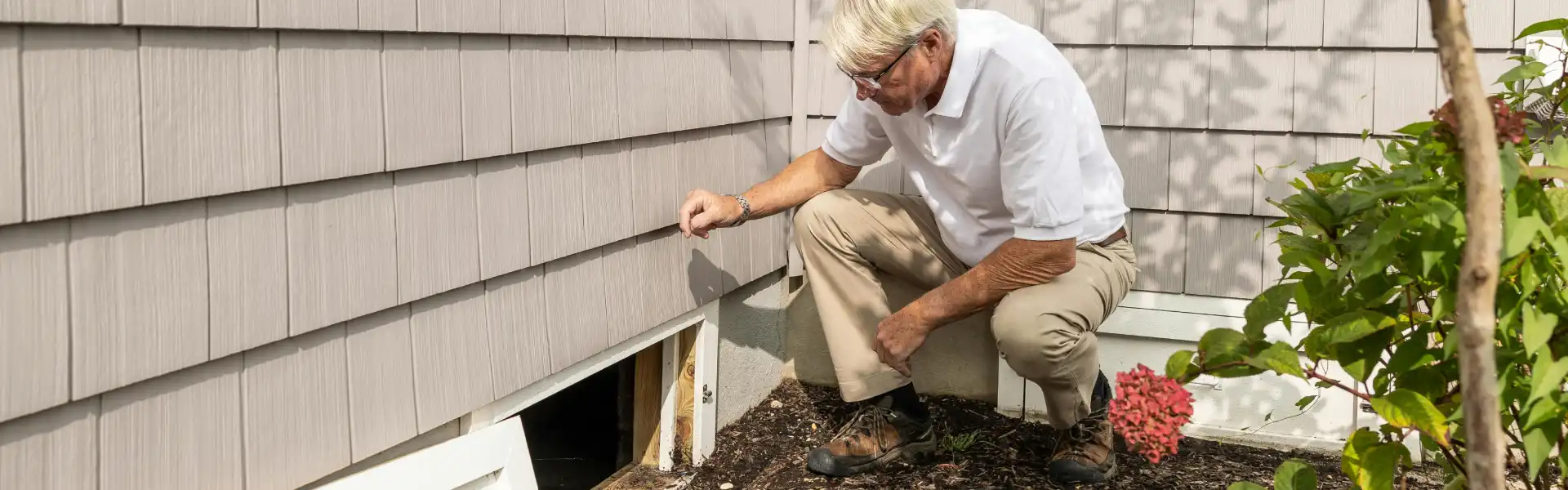 An Animal Remover technician opening a hatch to a crawl space. Animal Remover offers property animal inspections in Cincinnati.