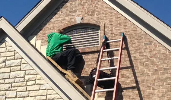 Animal Remover technician repairing animal exclusion services around a window